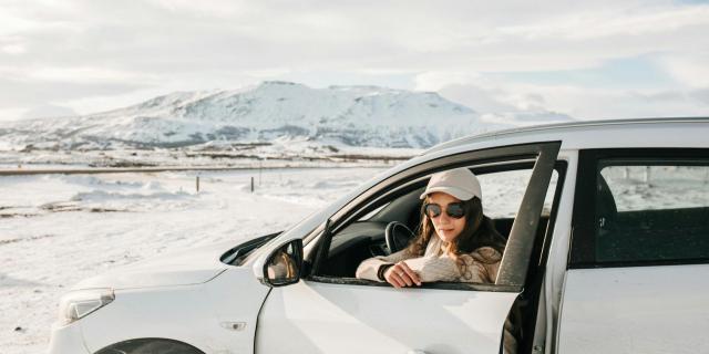 A woman sitting in a white car in a snowy landscape