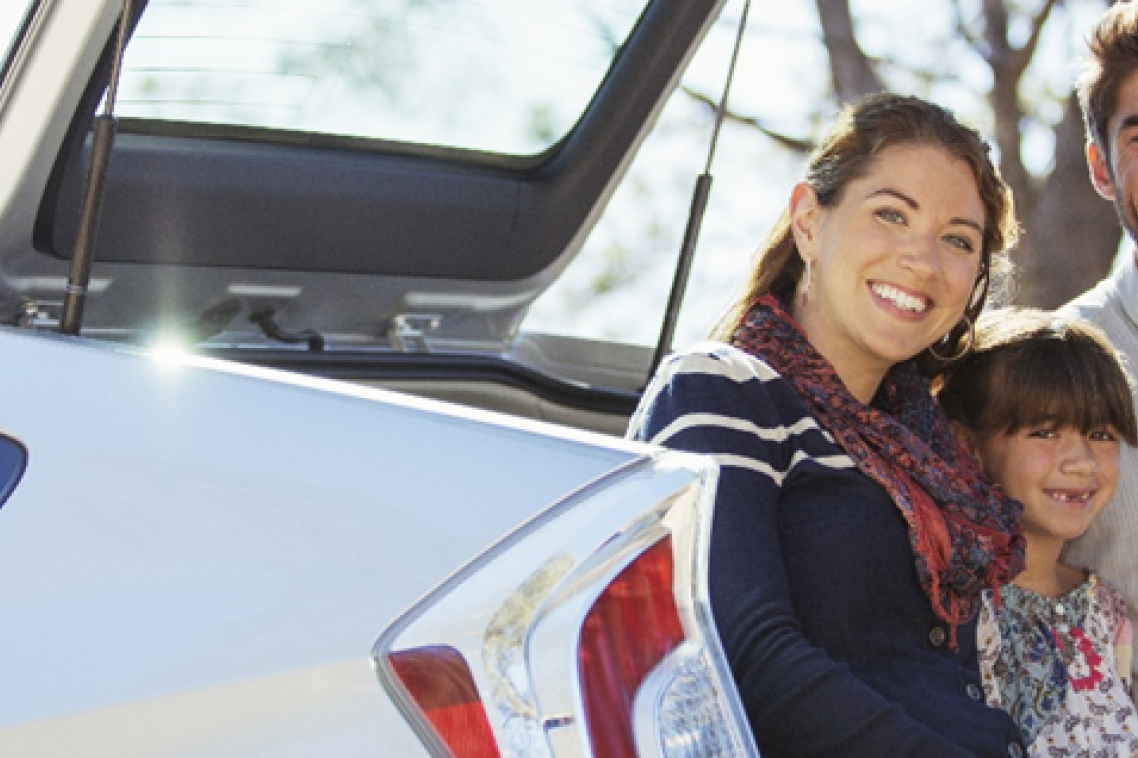 A family smiling at the back of their car